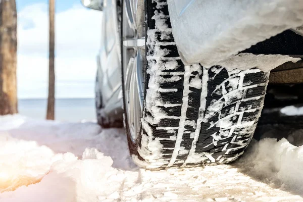 寒い季節に滑りやすい雪のドリフトカントリー未舗装道路を通って運転中に冬のトレッドタイヤと車のホイールのクローズアップ詳細ビュー。危険交通事故のリスク。季節のタイヤ交換コンセプト — ストック写真