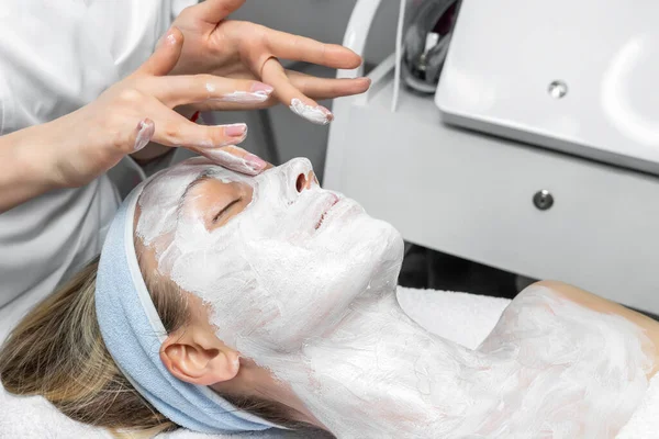 Közelkép kozmetikus orvos kezét, hogy anti-age eljárás, maszk és peeling fiatal vonzó női ügyfél a kozmetikai klinikán. Kozmetológus szakorvos bőrápoló kezelés.Egészségügyi terápia — Stock Fotó