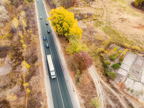 Aerial top view white semi trailer truck delivery shipment cargo courier moving fast on motorway road city urban suburb. Business distribution and logistics express service. Lorry driving highway day