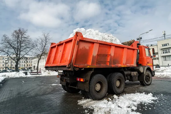 Máquina cargadora de tractores cargando nieve sucia en un camión volquete. Limpieza de la calle de la ciudad, la eliminación de la nieve y el hielo después de fuertes nevadas y ventiscas. Arado de nieve al aire libre acera pavimento limpio camino de entrada — Foto de Stock