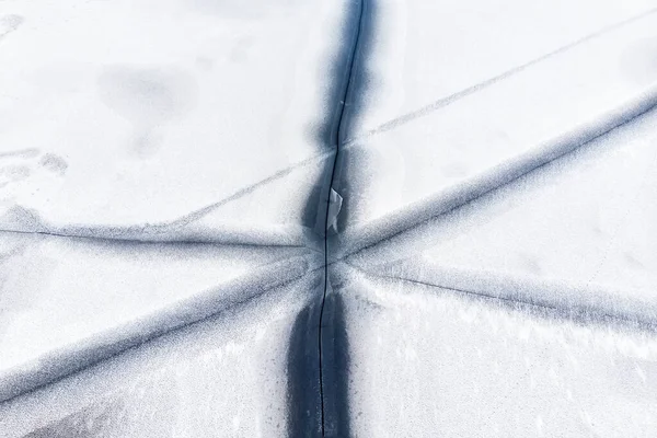 Légi drón tetején kilátás hó borított fagyasztott tó vagy folyó felszínén nagy repedt jég átlós vonalak. Természetes téli táj elvont textúra minta. Veszélyes tó olvadás az olvadási időszakban — Stock Fotó