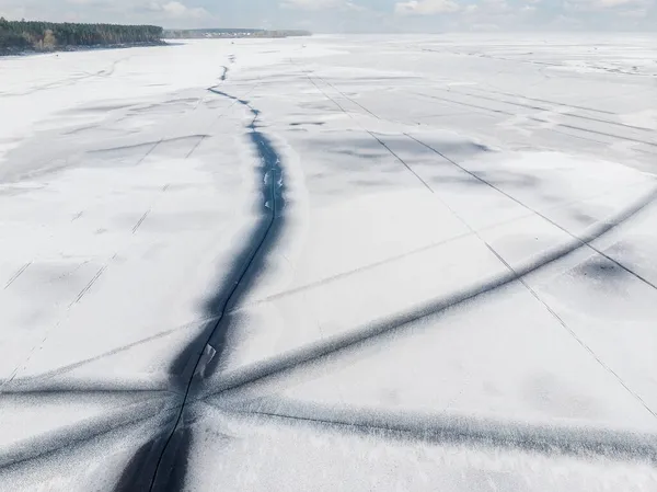 Dron z powietrza widok góry pokryty śniegiem zamarznięte jezioro lub powierzchni rzeki z dużych pękniętych linii przekątnej lodu. Naturalny krajobraz zimowy abstrakcyjny wzór tekstury. Niebezpieczne topnienie stawu w porze odwilży — Zdjęcie stockowe