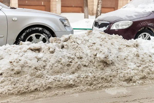 Ciudad calle camino de entrada estacionamiento con muchos coches cubiertos de nieve metida después de nevada fuerte ventisca en el día de invierno por la sucia pila nevada. Deriva de nieve y vehículos congelados. Condiciones meteorológicas extremas — Foto de Stock