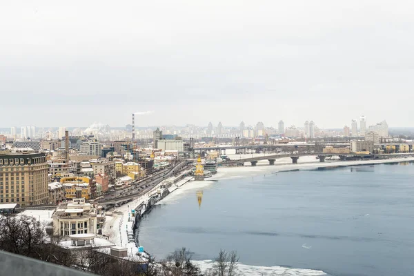 Scenic top panoramic view of Kyiv city Podol old center over ice covered Dnepr river Rybalskiy island panoramic landscape white winter snowfall. Cold season Ukrainian capital Kiev blizzard panorama — Stock Photo, Image