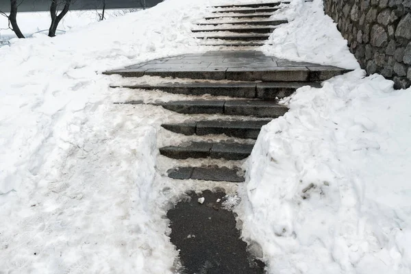 Бетонная каменная лестница, покрытая грязным глубоким скользким снегом после снежной бури на городской пешеходной дорожке. Слайд падения травмы опасность скольжения шаги. Зимняя холодная погода — стоковое фото