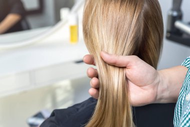 Yakın plan erkek, profesyonel kuaför, el ele tutuşan kadın uzun, parlak, altın sarısı saç tokası. Bayan müşteri, yeni saç stili ile Beaty Salonu 'na geri döndü. Saç bakımı ve tedavisi