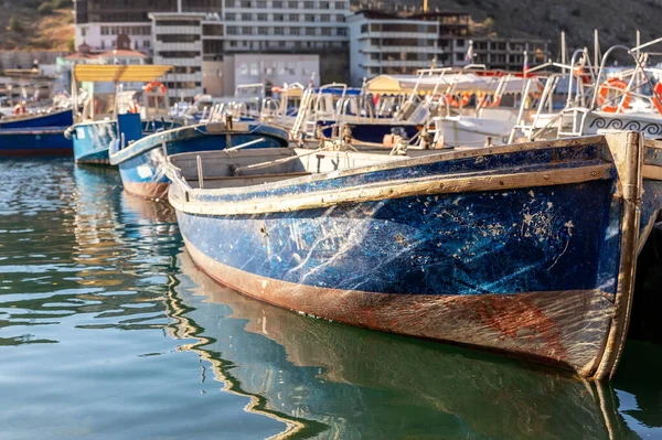 Yakından bakıldığında, parlak güneşli bir günde balıkçı köyü marinasına demirlemiş eski ahşap renkli parlak balıkçı gemileri görülüyor. Geleneksel geçmişe sahip deniz limanı