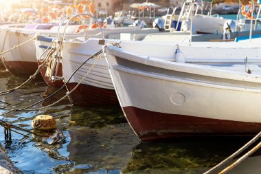 Parlak güneşli bir günde balıkçı köyü marinasına demirlemiş pek çok küçük, eski, ahşap renkli, parlak balıkçı teknesi. Geleneksel geçmişe sahip deniz limanı
