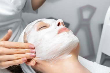 Güzellik uzmanının eli. Güzellik kliniğindeki genç ve çekici bayan müşterinin reşit olmama prosedürünü, maskesini ve kabuğunu çıkarıyor. Cilt bakımı uzmanı. Sağlık terapisi.