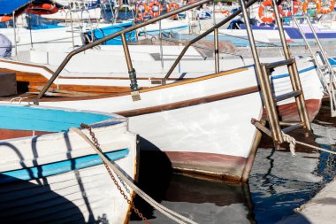 Parlak güneşli bir günde balıkçı köyü marinasına demirlemiş pek çok küçük, eski, ahşap renkli, parlak balıkçı teknesi. Geleneksel geçmişe sahip deniz limanı