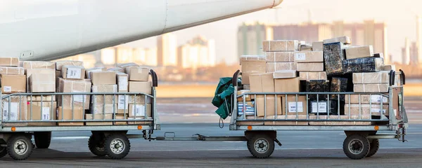 Turboprop kargo uçağına karşı ticari paketlerle dolu kargo vagonunun yakın çekim görüntüsü. Hava postası ve lojistik. Dışarıya aktarma işlemleri. Ticari charter uçuş servisi — Stok fotoğraf