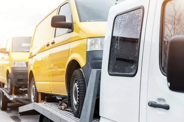 Λευκό μικρό φορτηγό φορτηγό φορτηγό όχημα φορτωμένο με δύο κίτρινο van minibus σε πλατφόρμα επίπεδης κρεβάτι και ημι ρυμουλκούμενο έλκει στην οδική οδική οδό. Μεταφορά εθελοντικής υποστήριξης για τους ανθρώπους της ουκραϊνίνας — Φωτογραφία Αρχείου