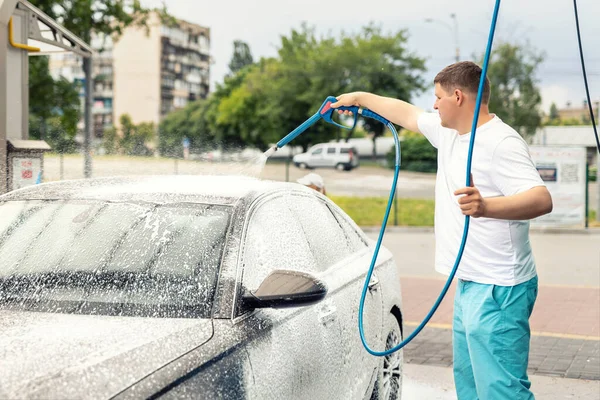 Aydınlık bir yaz gününde self-servis açık havada yüksek basınçlı su teçhizatı pompasıyla yakın plan araba yıkama. Araba oto yıkama servisi sırasında köpük şampuanla kaplı kimyasal deterjanlar.