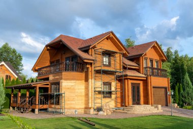 Modern ahşap ahşap eko villa ön cephesi yenileme işlemi sırasında, güneş yanığına karşı cila yapmak için kumlu duvar, kırsal köşkte kabuk böceği nemi. Ev dış onarım ve bakım