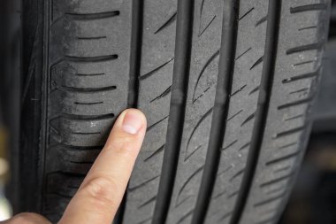 Tamirci, araba servisindeki lastik giyim göstergesini işaret ediyor. Araç tekerleği koruyucu kontrol ve bakım sırasında teftiş. Otomotiv bakımında lastik izi testi denetimi