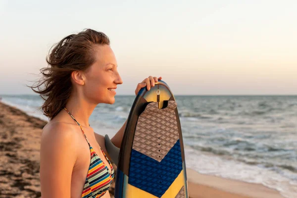 Πορτρέτο νεαρός ενήλικας λεπτό σπορ θηλυκό surfer κορίτσι με σανίδα του σερφ σιλουέτα σταθεί στο κύμα ακτή του ωκεανού κατά τη ζεστή ανατολή του ηλίου ή το ηλιοβασίλεμα. Αθλητισμός υγιή ξέγνοιαστη ελευθερία έννοια διακοπές τρόπο ζωής — Φωτογραφία Αρχείου