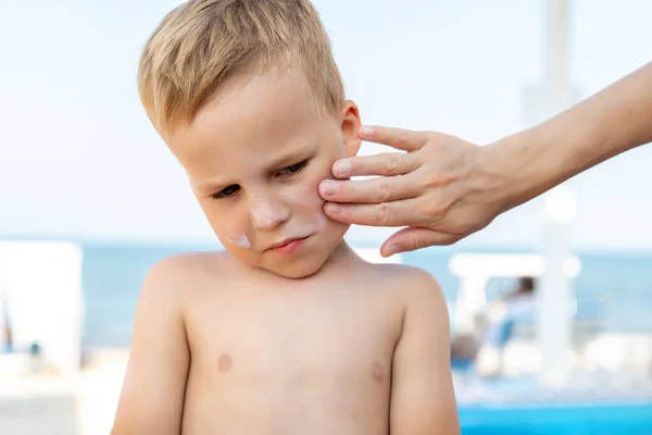 Moeder die zonnebrandcrème aanbrengt op schattige kleine baby jongen hand. Mama gebruikt sunblocking lotion om de baby te beschermen tegen de zon tijdens de zomervakantie. Reistijd voor kindergezondheidszorg — Stockfoto