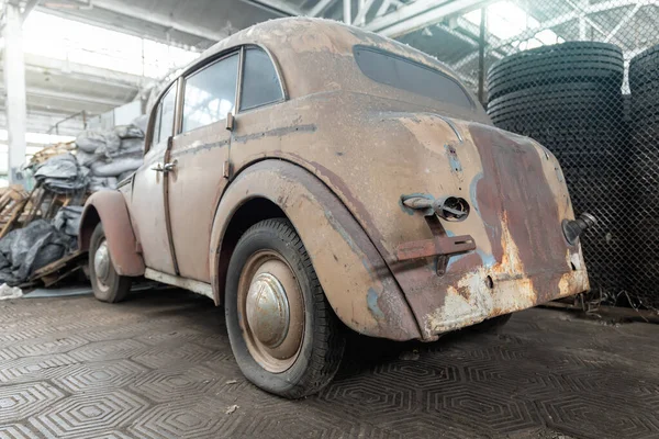 Back rusty abandoned forgotten antique oldtimer old car and motorcycles at junkyard factory storage warehouse indoors. Classic vintage retro vehicles detail garage workshop restore renovation station.