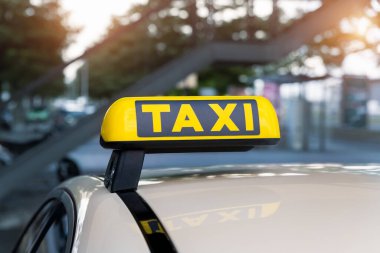 Otomobillerin üstündeki sarı taksi sembolü havaalanı terminalinin otoparkında ya da tren istasyonunda park sıcak akşamları Bokeh güneş ışığına karşı bekliyor. Kentsel sokak ulaşım konfor hizmeti.