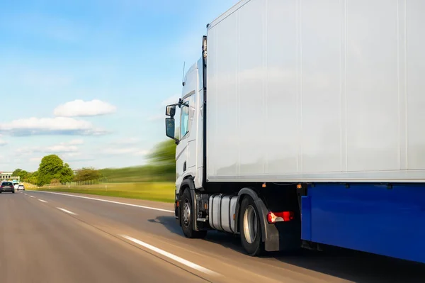 White blank modern delivery big shipment cargo commercial semi trailer truck moving fast on motorway road city urban suburb. Business distribution logistics service. Lorry driving highway sunny day.