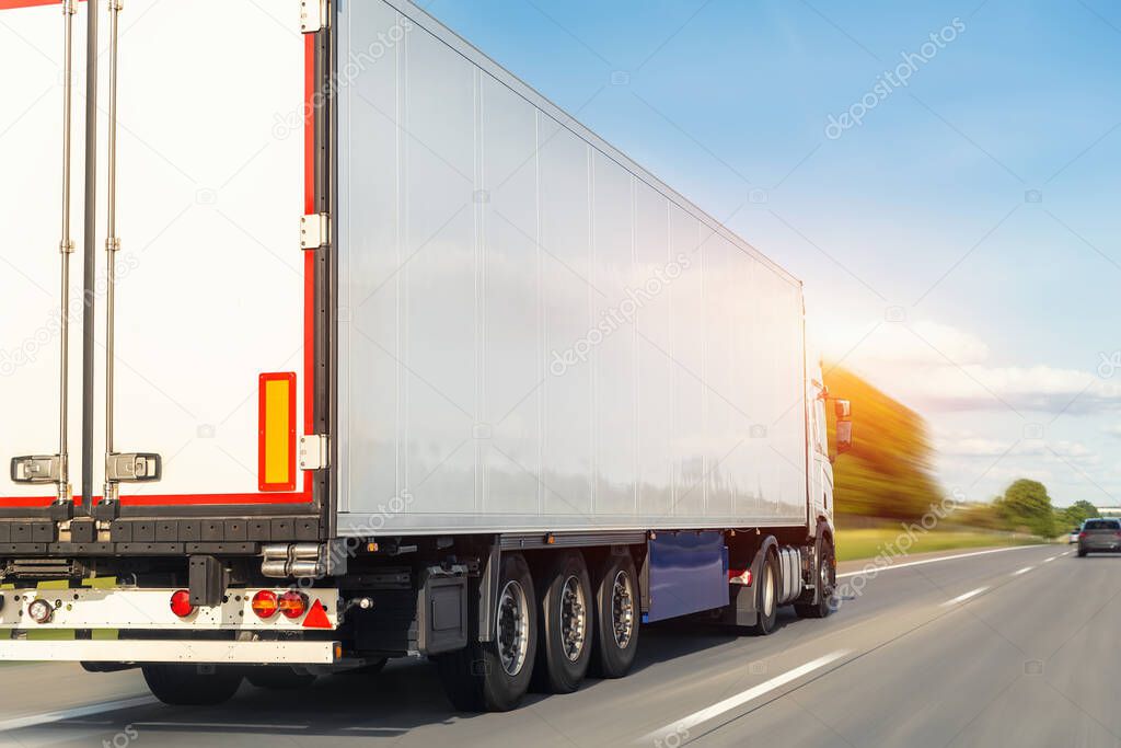 White blank modern delivery big shipment cargo commercial semi trailer truck moving fast on motorway road city urban suburb. Business distribution logistics service. Lorry driving highway sunny day.
