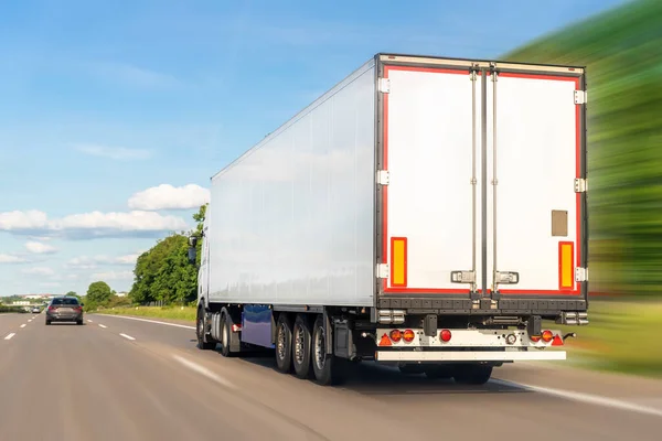 White blank modern delivery big shipment cargo commercial semi trailer truck moving fast on motorway road city urban suburb. Business distribution logistics service. Lorry driving highway sunny day.