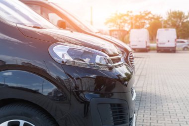 Yakın plan, günbatımına karşı araba kiralama şirketine park etmiş birçok modern lüks siyah minibüsün ön far görüntüsü. Ticari kargo taşıma şirketi filosu. Vip tüzüğü.