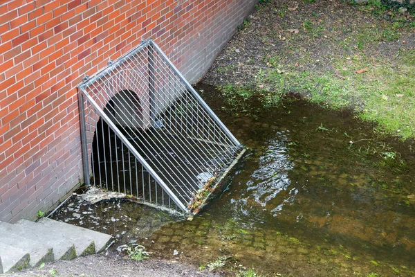 Metal grid storm drain filter barrier. Clean water city channel spring. Grate rain drainage sewage garbage pollution protection. City urban infrastructure.