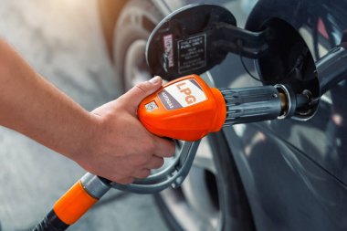 Close-up detail view of fuel autogas pump gun connected with noozle adapter to car tank to refill at car gas filling station. Refueling vehicle with liquefied lpg or lng product. Safety technology.