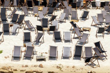 Scenic water view of many empty black wooden deckchair loungers on sand river or sea ocean beach. Rows of deckchair on closed coast due contamination. Lack of people tourist on resort due sanctions.