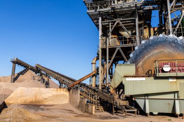 Close-up detail part of heavy metal construction of open pit gravel plant sand quarry big rusty rotor machine material excavating and crushing. Industrial machinery factory equipment steel background.
