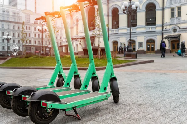 Birçok modern yeşil elektrikli scooter park edilmiş şehir caddesini paylaşıyor. self-servis sokak taşımacılık kiralama servisi. Akıllı telefon uygulaması olan şehir içi hareketlilik aracı kirala. Sıfır emisyon yeşil eko enerji.