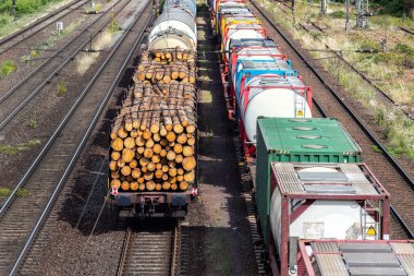 Above view of railway sorting station with many lines directions in Germany. Railroad car wooden timber logs and gas tanks logistics. Raw wood heating material transportation. Freight cargo transport.