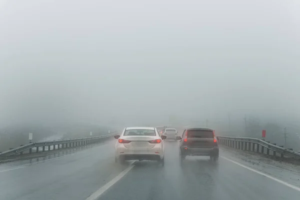 Car overtake rules violation crossing double lane. traffic on foggy misty rainy highway intercity road low poor visibility cold winter autumn day. Seasonal bad rainy weather accident danger warning.