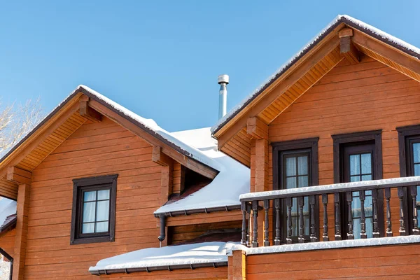 Scenery facade front view of modern wooden luxury timber eco house villa with garage door snowcapped by white fresh snow at cold sunny winter day. Real estate building construction project exterior.