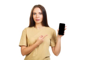 Genç kız akıllı telefonun siyah ekranını işaret ediyor. Beyaz bir arkaplanda izole edilmiş.