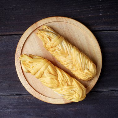 Koyu ahşap masanın üzerinde tütsülenmiş peynir.