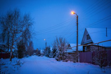 Köyde kış sokağı, alacakaranlıkta fenerlerle