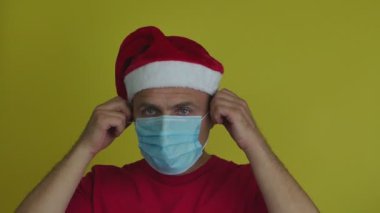 Noel Baba şapkalı bir adam maskesini rahatça çıkartıyor..