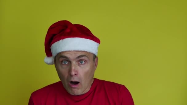 Um homem engraçado e alegre em um chapéu de Papai Noel joga uma caixa de presente. — Vídeo de Stock