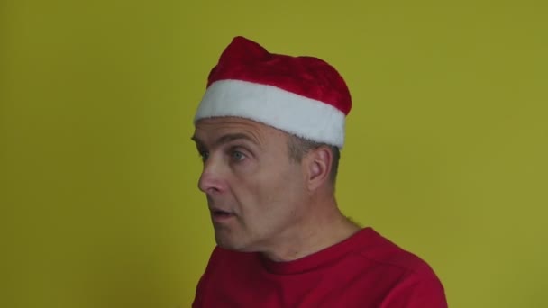 Een man met een kerstmuts draagt een medisch masker op zichzelf.. — Stockvideo