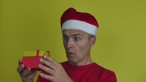 O homem do chapéu de Pai Natal tira a máscara médica da caixa de presente e coloca-a. — Vídeo de Stock