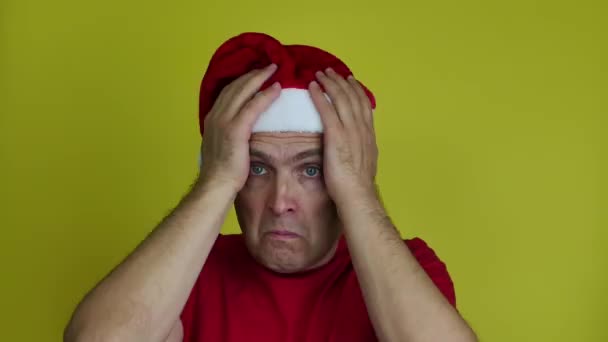 Portrét rozrušeného muže v Santově klobouku držícího hlavu. — Stock video