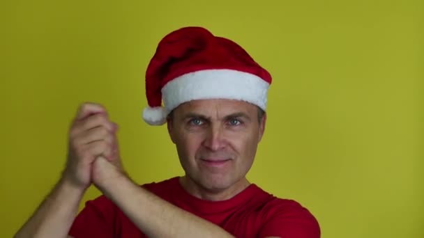Een knappe man met een kerstmuts drukt zijn emoties uit met handgebaren.. — Stockvideo