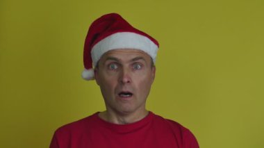 Noel Baba şapkalı korkmuş bir adam tıbbi maske takıyor..