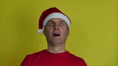Noel Baba şapkalı 40-55 yaşlarında yakışıklı bir adam ellerini çırpıyor ve alkışlıyor..
