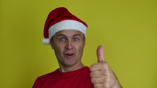 Man met kerstmuts maakt gebaar met duimen van beide handen. — Stockvideo