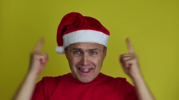 Um homem bonito de chapéu de Pai Natal expressa suas emoções com gestos de mão. — Vídeo de Stock