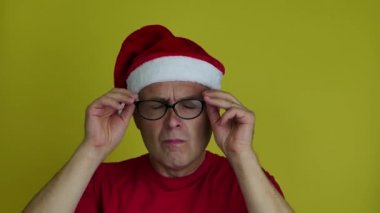 Noel Baba şapkalı adam şaşkınlıkla gözlüklerini çıkarıyor..