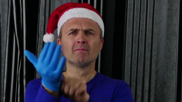 El hombre del sombrero de Santa usa guantes médicos azules.. — Vídeos de Stock